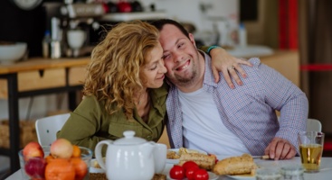 Mann mit Downsyndrom und Frau am Frühstückstisch