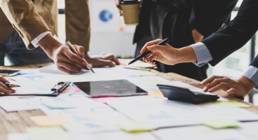 Tisch mit Dokumenten und Menschen, die damit arbeiten